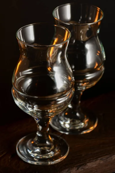 Dois copos de cerveja tulipa vazios na mesa de madeira escura sobre fundo preto . — Fotografia de Stock