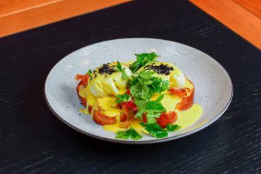 Vegetable salad with sause served on a blue plate on dark rustic wooden table in restaurant.
