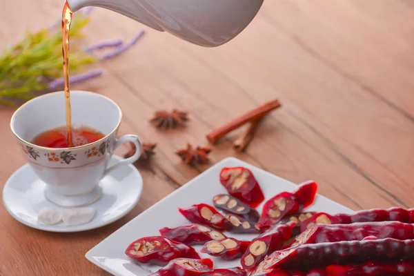 Tasty oriental sweets. Caucasian delicacy churchkhela - georgian nut treats. Served with a glass of tea and a tea pot. — Stock Photo, Image