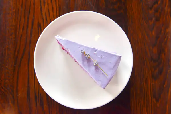 Slice of purple lavender cake with berries served with lavender flowers on a white plate. — Stock Photo, Image