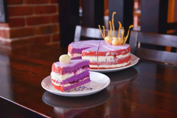 Skiva lila lavendelkaka med bär serveras med lavendel blommor på en vit platta. — Stockfoto