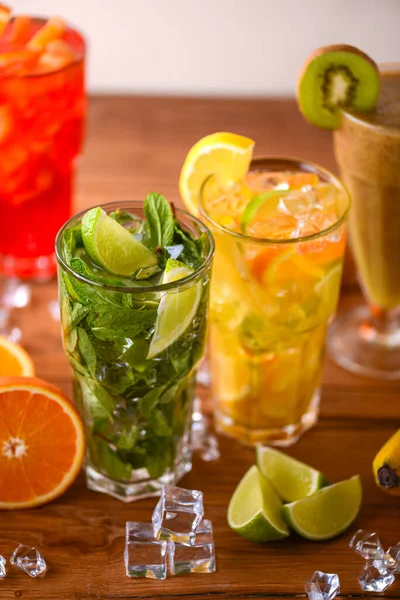 Cztery tropikalne napoje mieszane, koktajle pomarańczowe, cytrynowe i malinowe podawane na jasnodrewnianym stole. — Zdjęcie stockowe