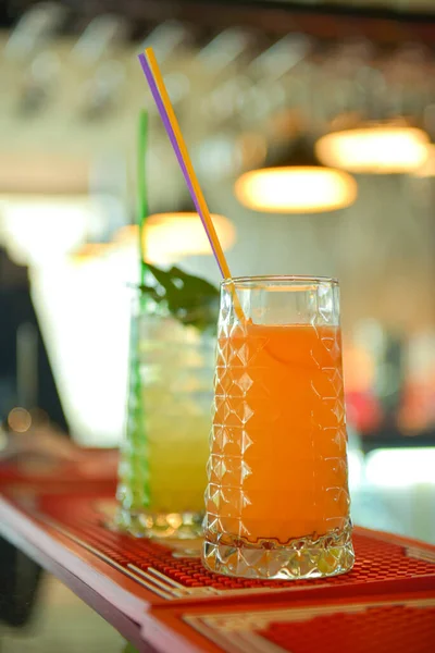 Cóctel de alcohol frío de verano con hielo y fruta en un vaso alto sobre fondo claro borroso restaurante o cafetería . — Foto de Stock