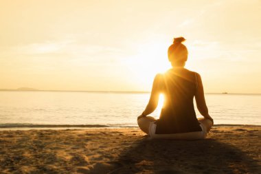 gün batımında sahilde Yoga uygulamak siluet genç kadın.