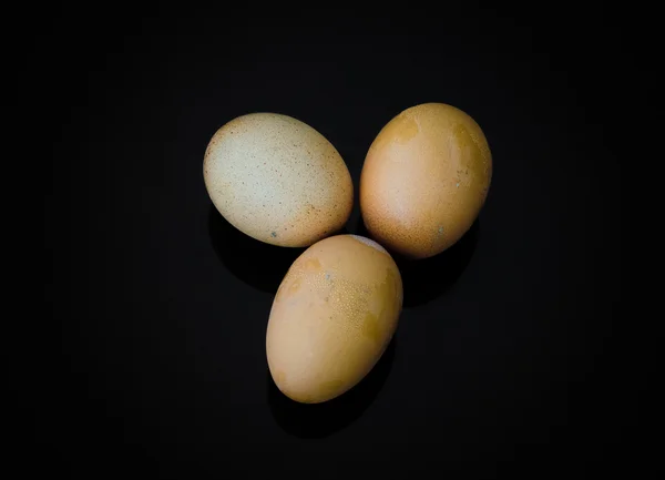 Trois œufs avec coquille sur fond noir — Photo