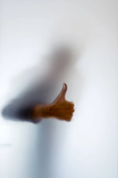 Egy ember a hüvelykujjával felfelé mögött tejüveg homályos alakja — Stock Fotó