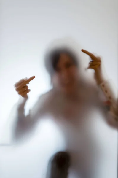 Onscherpe afbeelding van een vrouw met haar middelvinger achter froste — Stockfoto