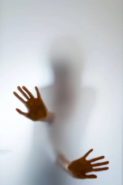 Shadowy human figure behind a frosted glass