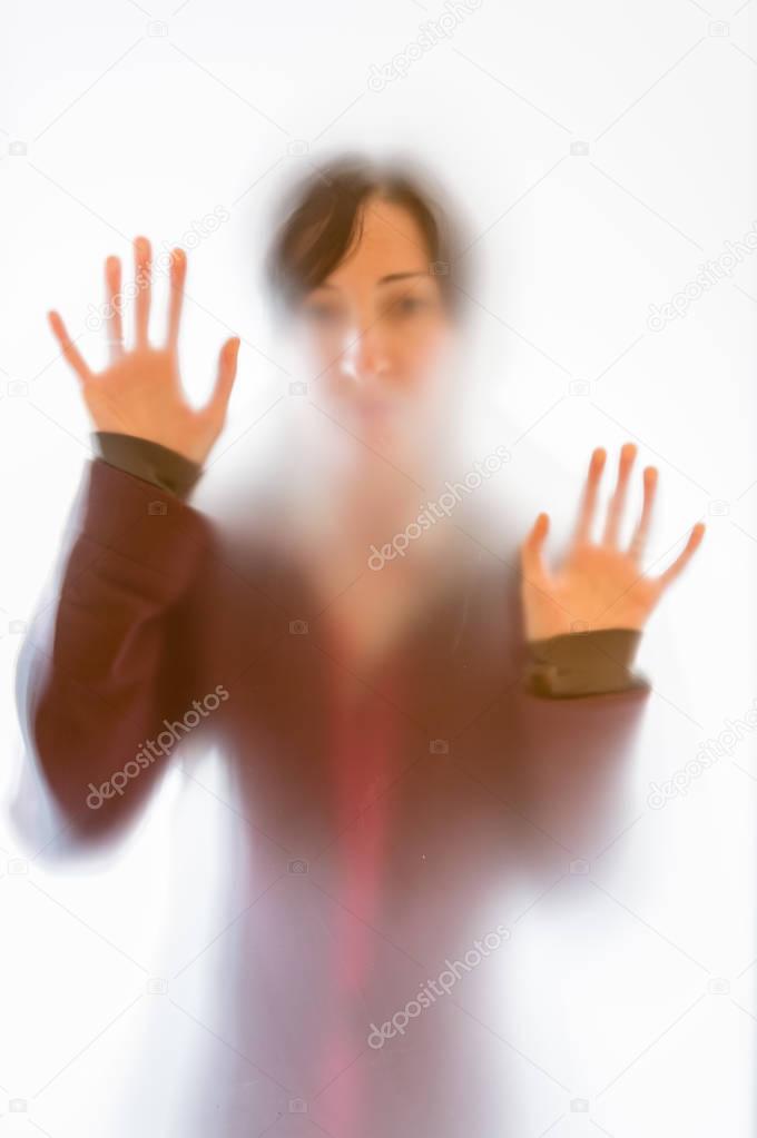 Shadowy woman figure behind a frosted glass