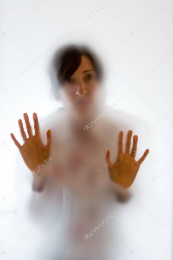 Shadowy woman figure behind a frosted glass