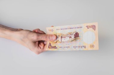 Elli Bhutan Ngultrum banknot elinde tutan kadın