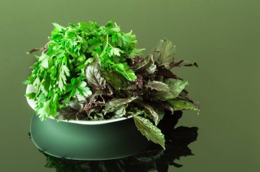 Taze maydanoz ve bir siyah yansıtıcı tabloda mor fesleğen