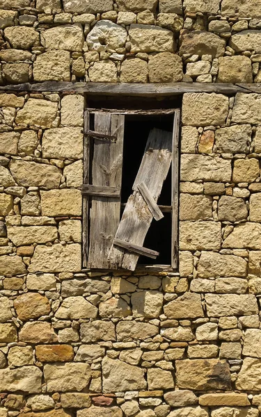 Gammalt fönster med trasig träslutare på en stenbyggnad — Stockfoto