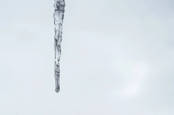 Ледяные сосульки, свисающие с крыши на ярком фоне неба — стоковое фото