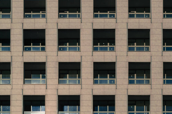 Several windows in a row on facade of urban apartment building front view