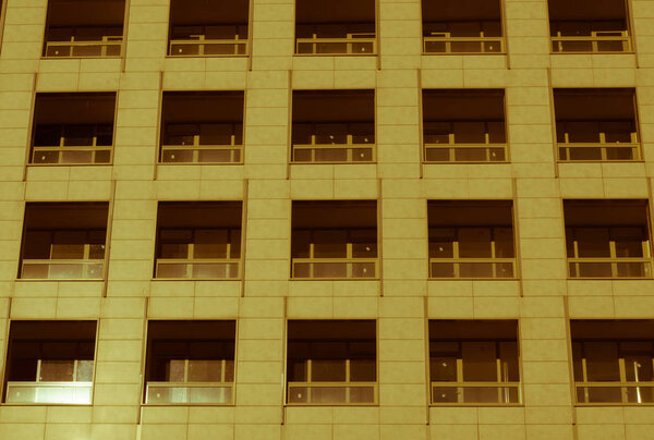 Several windows in a row on facade of urban apartment building front view