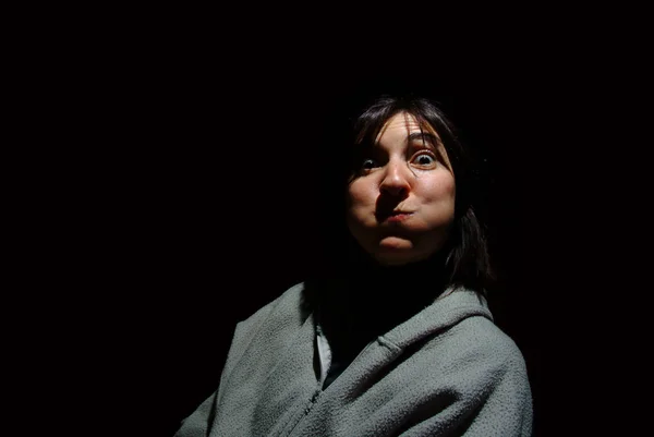 Young brunette woman blowing out her cheeks over black backgroun — Stock Photo, Image