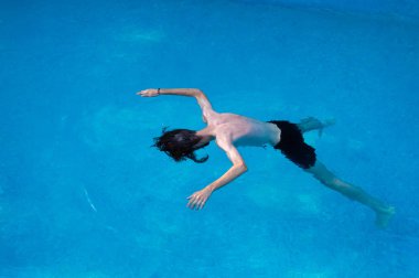 Yüzen ve havuzda eğleniyor genç adam 