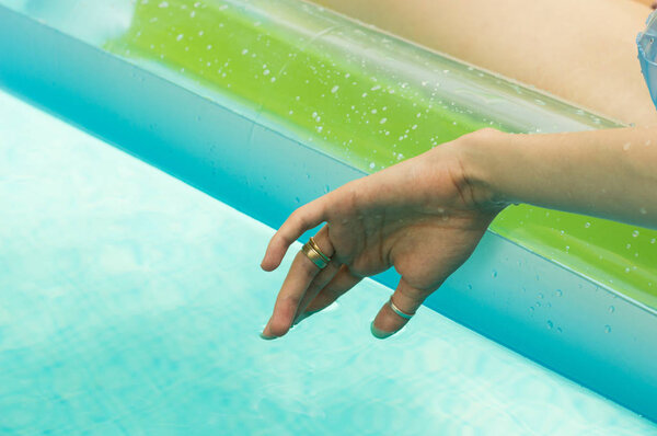 Молодая женщина, плавающая рукой в бассейне
