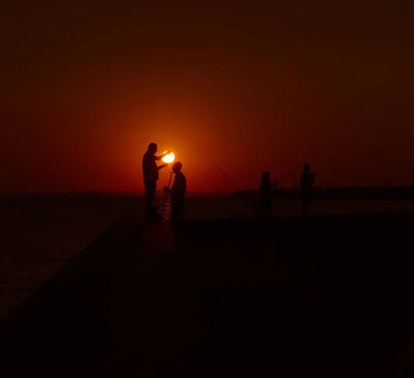 Silhouettes de pêcheurs au bord de la mer au coucher du soleil — Photo