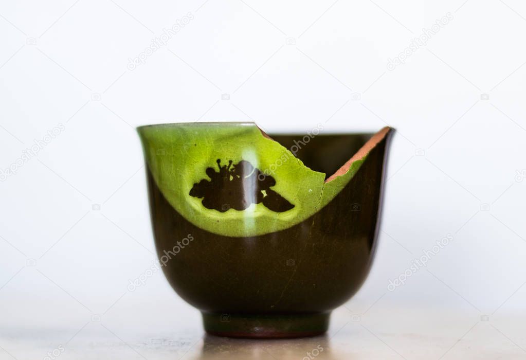 Broken green ceramic cup isolated on white background