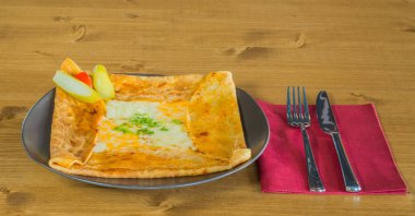 Kaşar peynir ve turşu yanında lezzetli krep gri bir tabakta