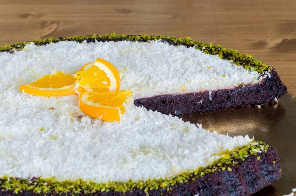 Close-up van een gesneden heerlijke chocolate cake met kokosnoten en stukjes sinaasappel — Stockfoto