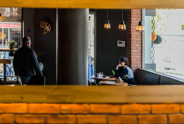 Vista refletida de uma loja de café e clientes em um espelho em uma parede de tijolo — Fotografia de Stock
