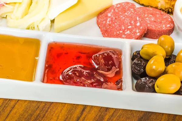 Closeup of traditional Turkish breakfast served in porcelain plate with olive, jam, salami, cheese, honey and sausage Stock Image