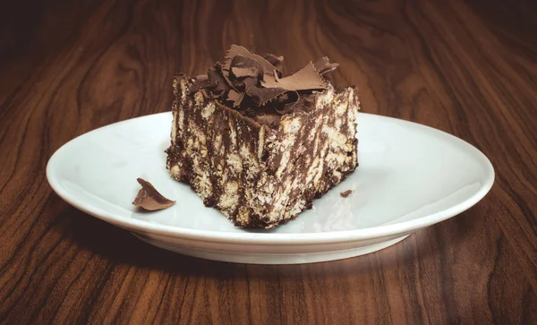 木製テーブルの上の白い皿にて、おいしいモザイク チョコレートとビスケット ケーキ — ストック写真