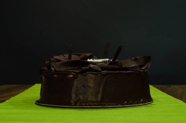 Lezzetli kremsi bütün karanlık çikolatalı kek koyu arka plan üzerinde