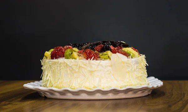 暗い背景の上にフルーツと全体の白のクリーミーなおいしいチョコレート ケーキ — ストック写真