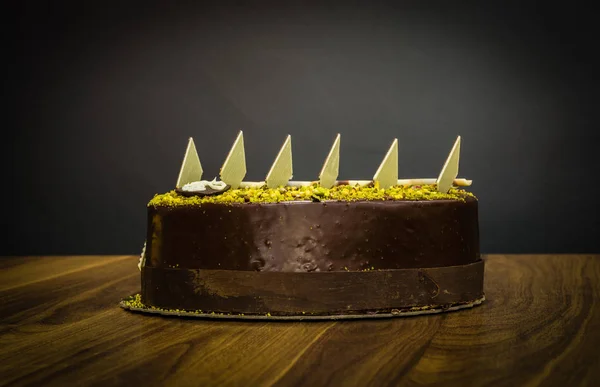 暗い背景にトッピングにピスタチオおいしいクリーミーな全体暗いチョコレート ケーキ — ストック写真