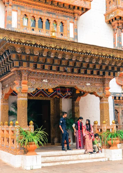 Thimphu, Bután - 10 de septiembre de 2016: Guardia del palacio real butanés con mujeres locales vestidas con ropa tradicional frente a la entrada de un edificio tradicional . — Foto de Stock