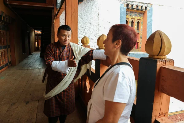 Thimphu, Bután - 10 de septiembre de 2016: Guía turística butanesa que muestra el templo al turista en el balcón . — Foto de Stock