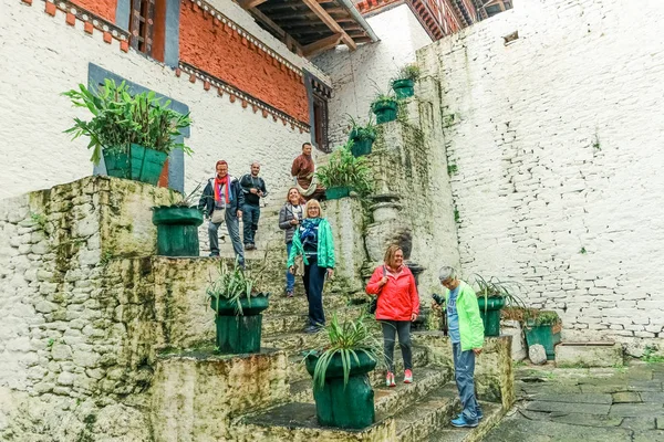Trongsa, Birleşik Arap Emirlikleri - 12 Eylül 2016: Mutlu turist grubu ayakta Trongsa Dzong, Bhutan avlusunda merdivenlerde