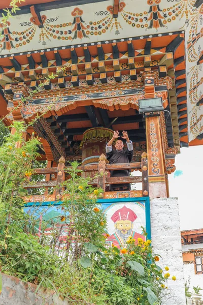 Thimphu, Bután - 15 de septiembre de 2016: Vista de bajo ángulo de un feliz saludo monje frente a la rueda de oración en Simtokha Dzong, Thimphu, Bután, Asia del Sur — Foto de Stock