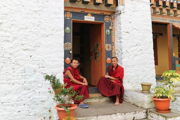 Thimphu, Bután - 15 de septiembre de 2016: Dos jóvenes monjes sonrientes sentados frente a la puerta en Simtokha Dzong, Thimphu, Bután, Asia del Sur — Foto de Stock