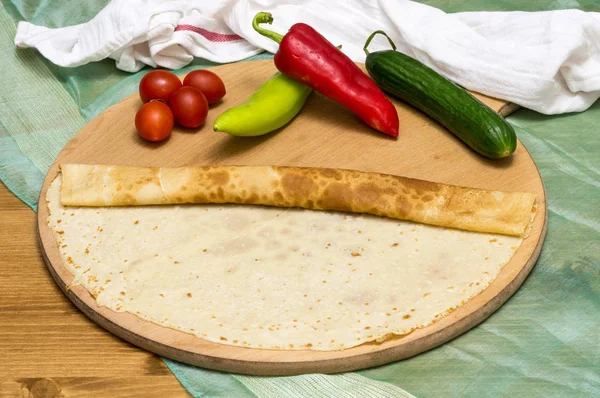 Rolled crepe, Russian blini on wooden cutting board with cherry tomatoes, green and red peppers, and cucumber — Stock Photo, Image