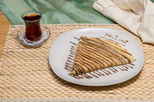Crepe plegado, blini ruso con salsa de chocolate en plato blanco servido con té turco — Foto de Stock