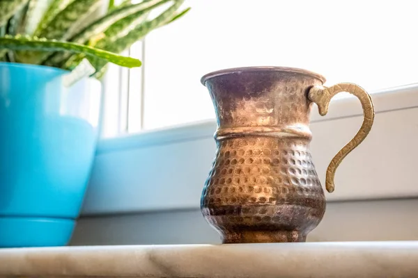 Tazza di rame con manico vicino alla finestra — Foto Stock