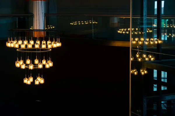 Gran lámpara de araña con luces amarillas pendientes en un edificio de techo alto —  Fotos de Stock