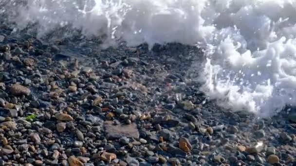 Powolny ruch fale morskie z białą pianką myjącą kamienie żwirowe na plaży — Wideo stockowe