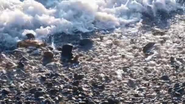 Slow motion sea waves with white foam washing up pebble stones on the beach — Stock Video