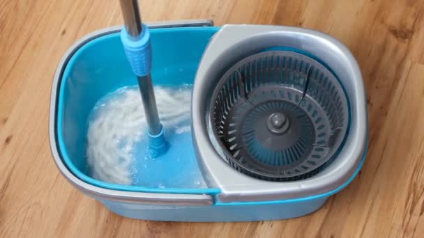 Washing and spinning the flat mop telescopic handle in a blue bucket filled with water and detergent. — Stock Video