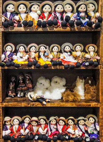 Muñecas de tela tradicional sudamericana hechas a mano en ropa tradicional exhibida en estantes en el mercado de artesanía indígena —  Fotos de Stock