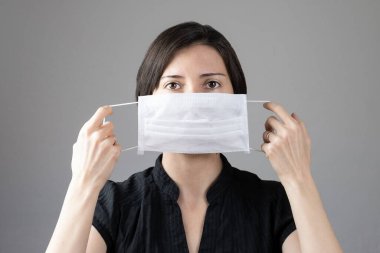 Enfeksiyonu önlemek için hijyenik maske takan esmer kadın grip gibi hava yoluyla bulaşan solunum hastalıkları gri arka planda 2019-nCoV. Sağlık hizmetleri kavramı.