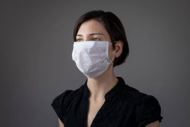 Enfeksiyonu önlemek için hijyenik maske takan esmer kadın grip gibi hava yoluyla bulaşan solunum hastalıkları gri arka planda 2019-nCoV. Sağlık hizmetleri kavramı.