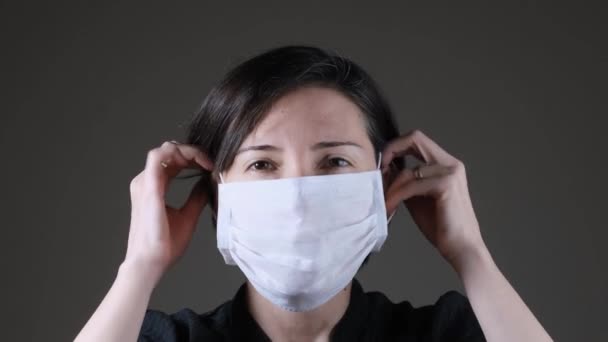 Portrait of a Caucasian woman wearing and taking off a white medical mask. Protection against contagious disease, coronavirus — Stock Video