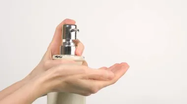 Beyaz kadın dezenfektan jel pompasına basıyor ve avucundaki yumuşak sabun jelini sıkıyor.
